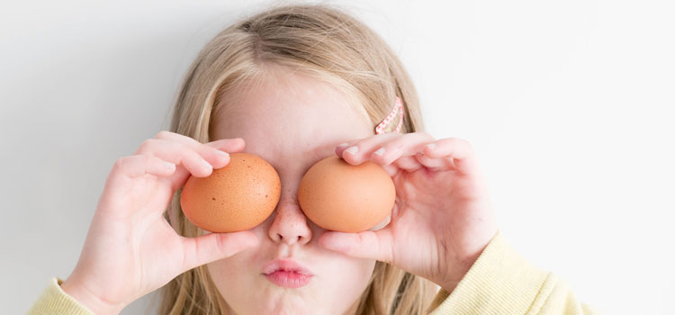 girl holding eggs over eyes