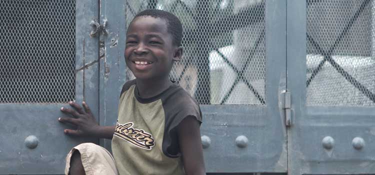 a boy smiling near a fence