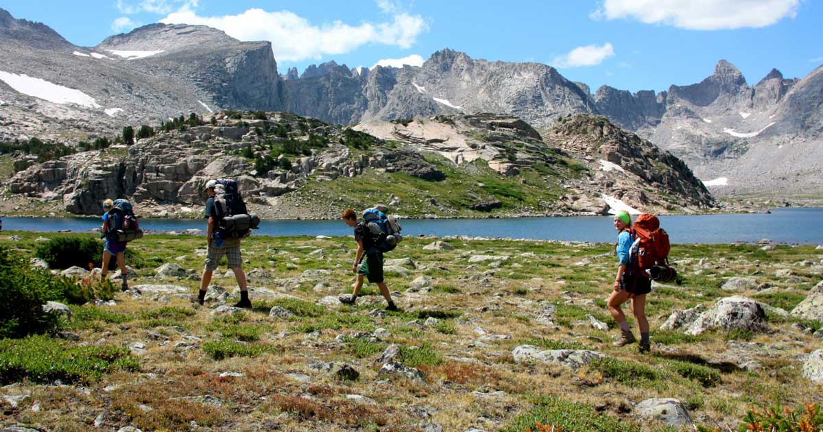 a group of people backpacking in the mountains