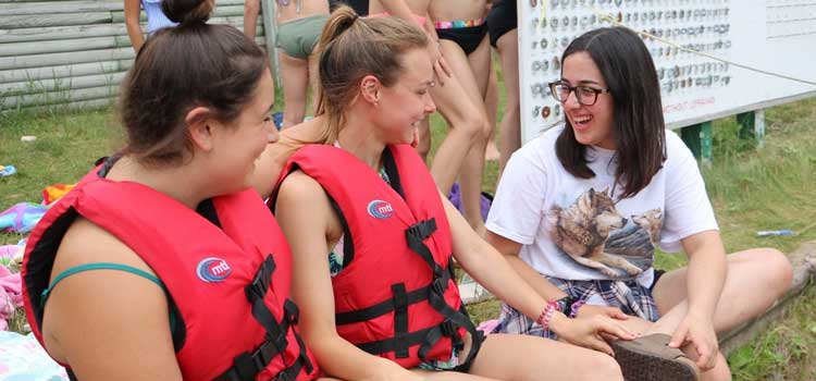 camp counselor talking to two girls in life vests
