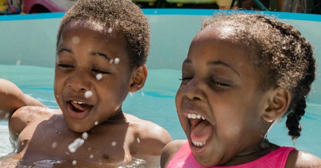 three kids smiling in a pool