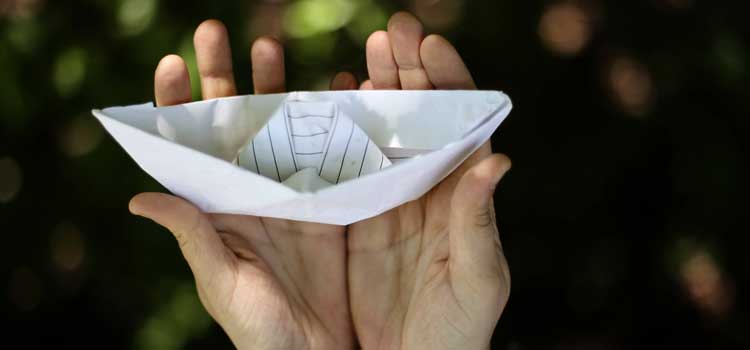 Person holding a paper boat