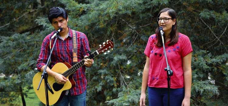 two people singing at microphones one with a guitar at a summer camp group activity
